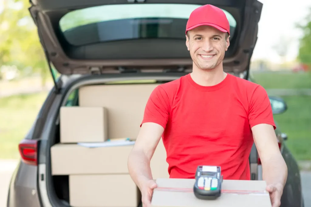 delivery worker in red uniform holding package with card payment terminal
