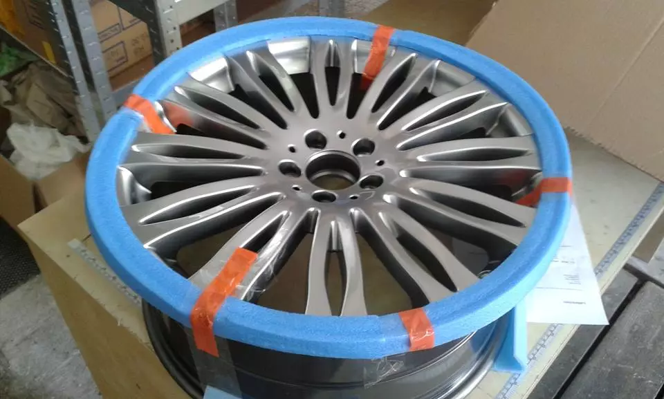 car alloy wheel with blue foam rim protector placed on workbench